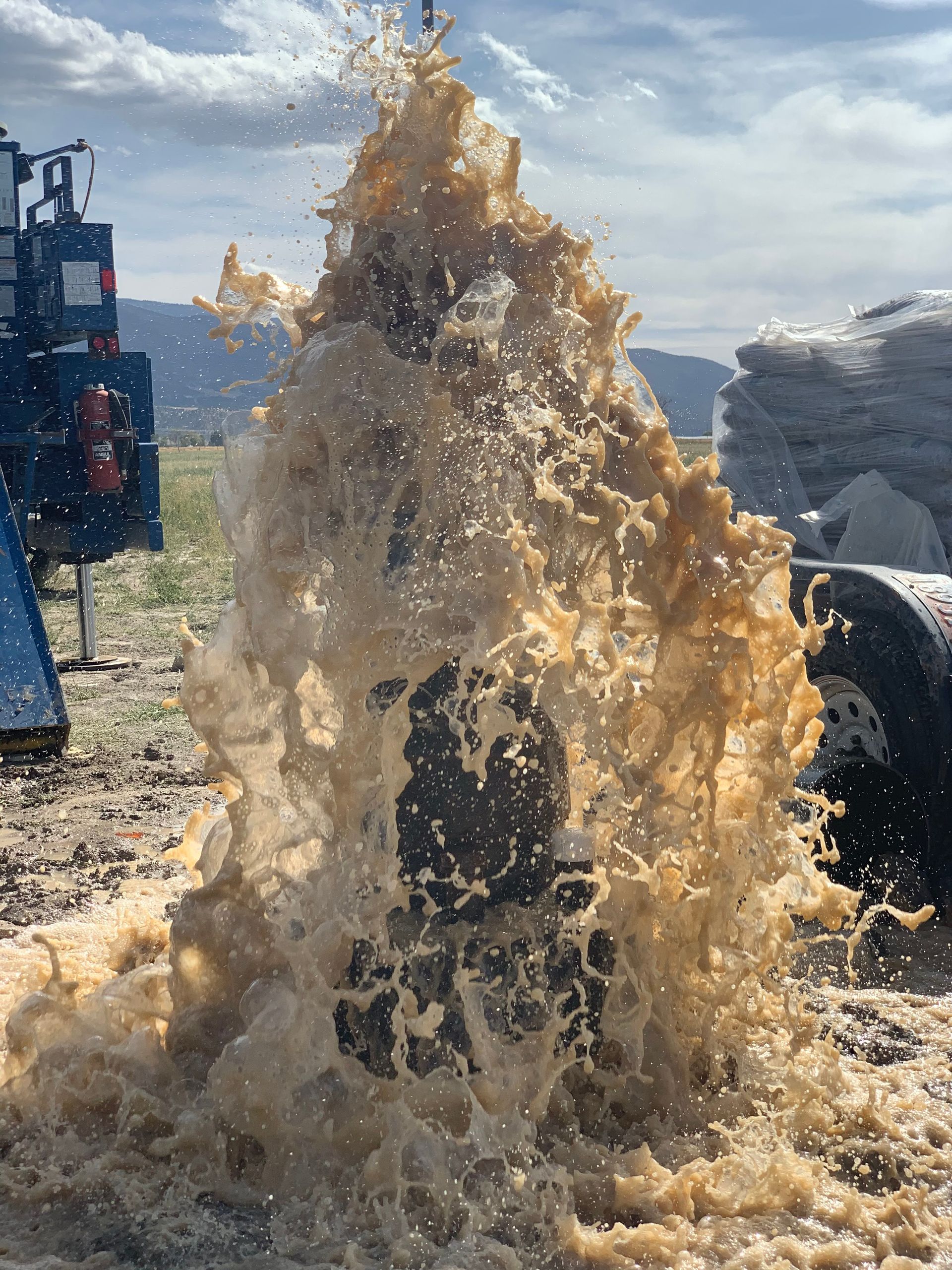 A large splash of water is coming out of a hole in the ground.