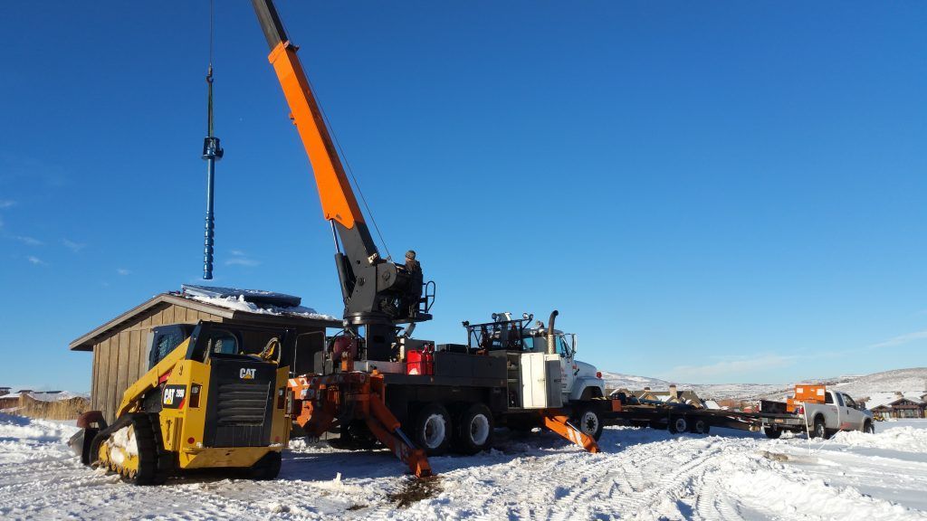 A crane is lifting a piece of equipment in the snow