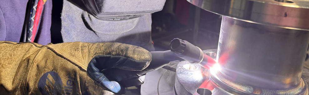 A man is welding a piece of metal in a factory.