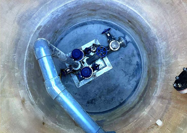 A blue pipe is coming out of a hole in the ground.