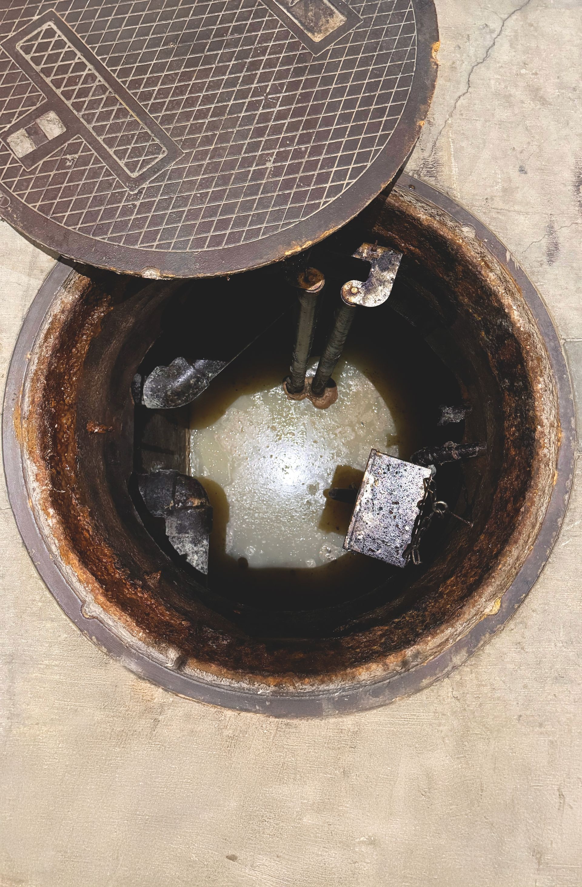 A manhole cover is open and filled with water.