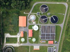 An aerial view of a sewage treatment plant surrounded by grass and trees.