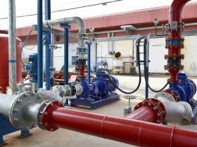 A bunch of red pipes and pumps in a factory.