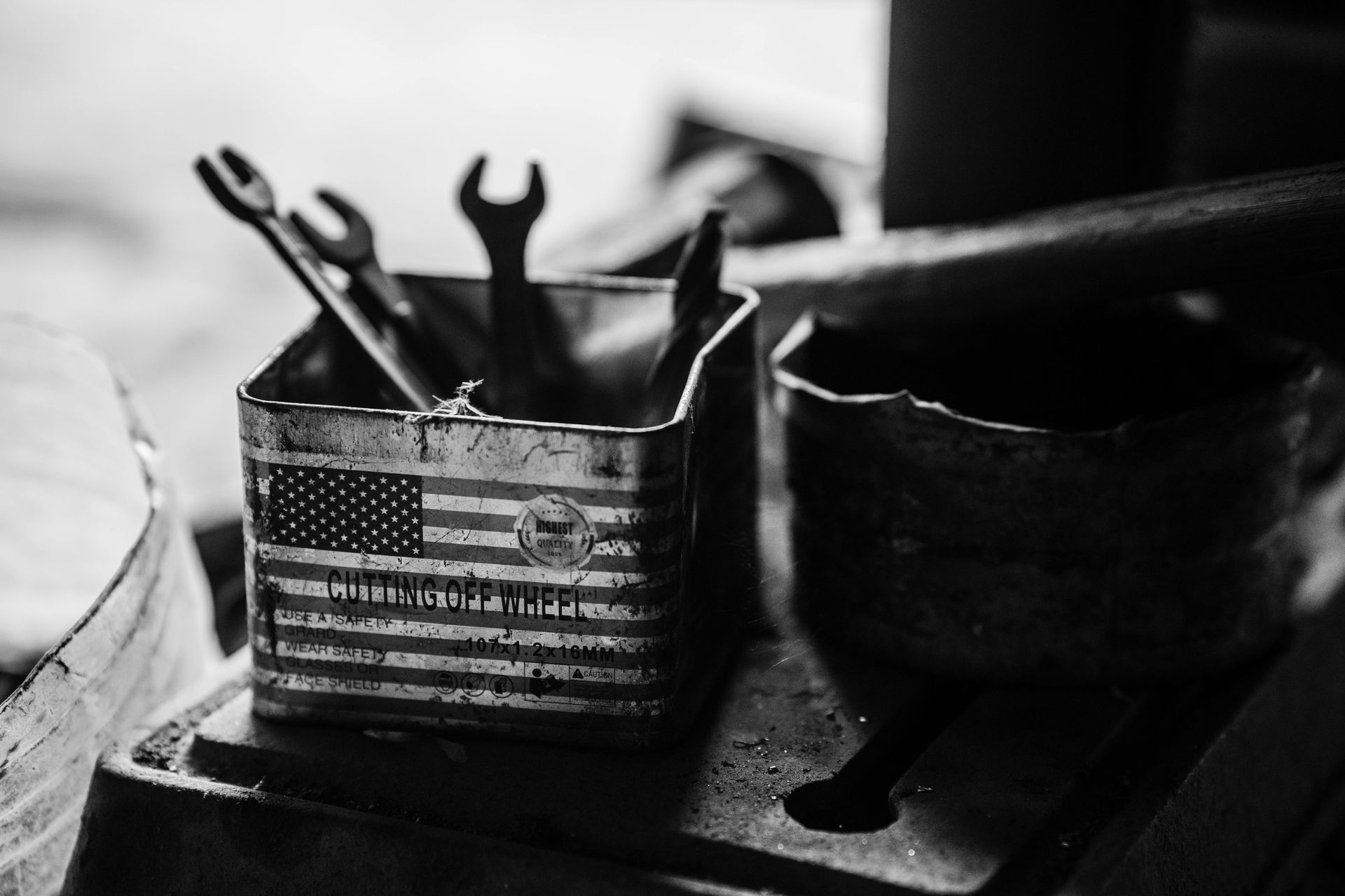 Metal toolbox with wrenches on a workbench, featuring a U.S. flag design
