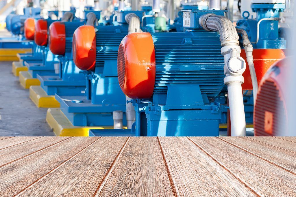 A row of blue and orange pumps are lined up in a factory.