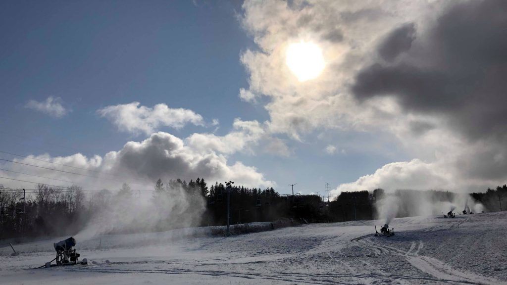 A person is riding a snowmobile down a snow covered slope.