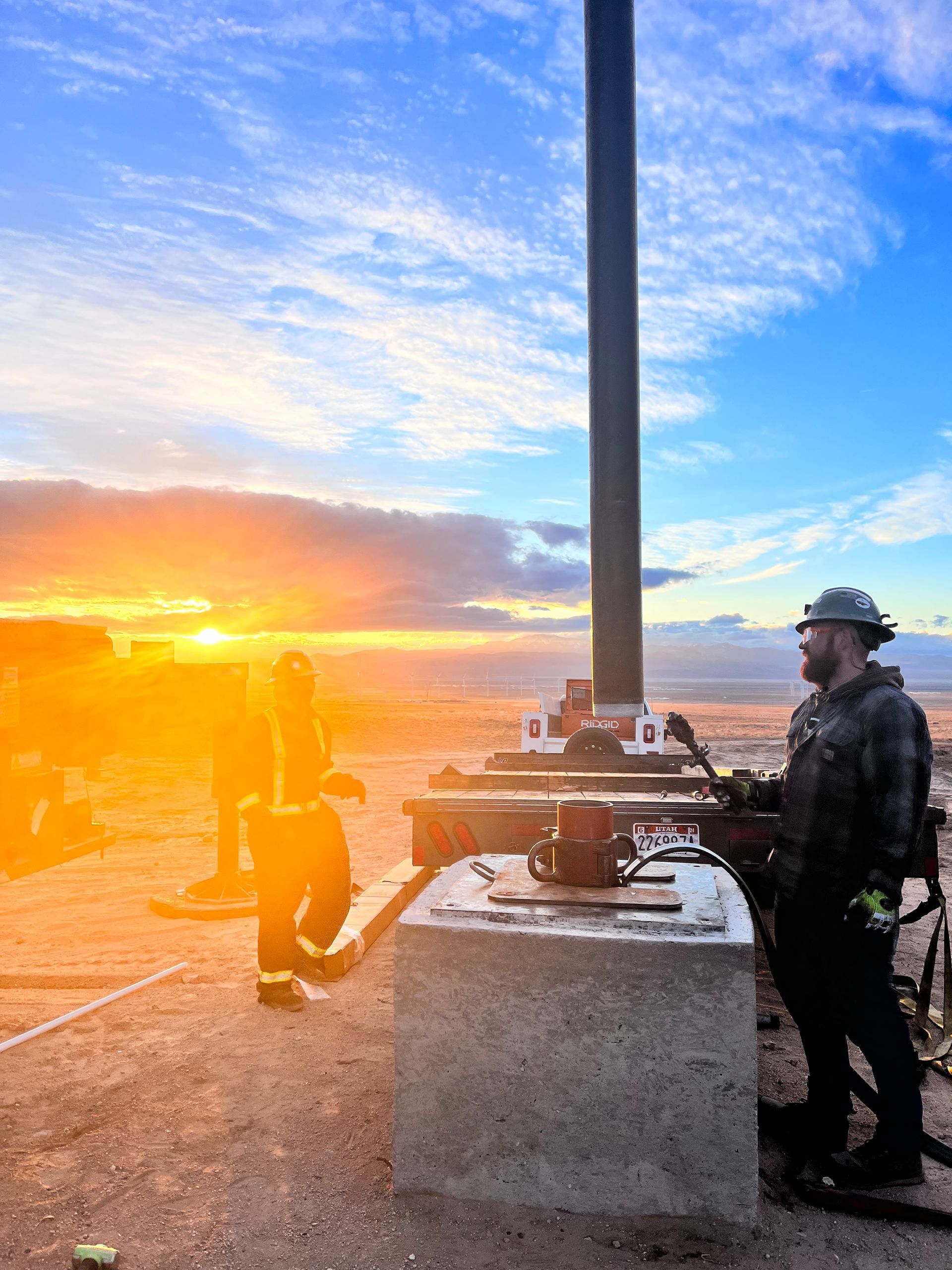 A man is standing next to a pole with a sunset in the background.