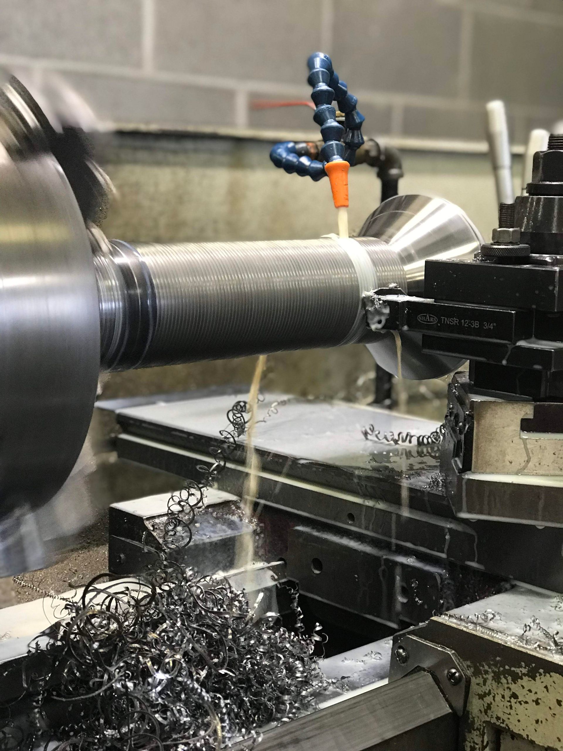 A machine is cutting a piece of metal on a lathe.