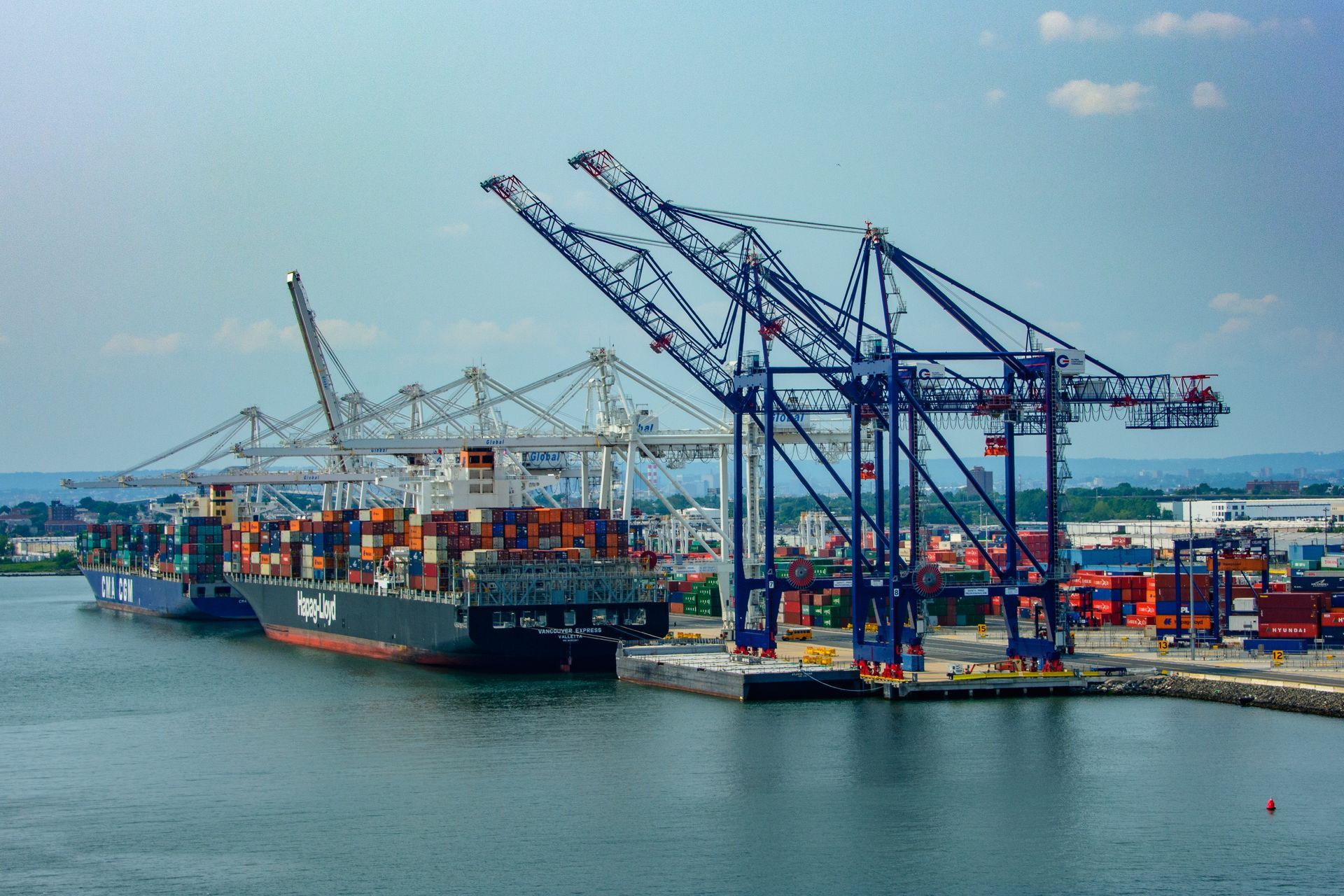 Port of Bayonne, NJ with a container ship, multiple large cranes, and numerous shipping containers