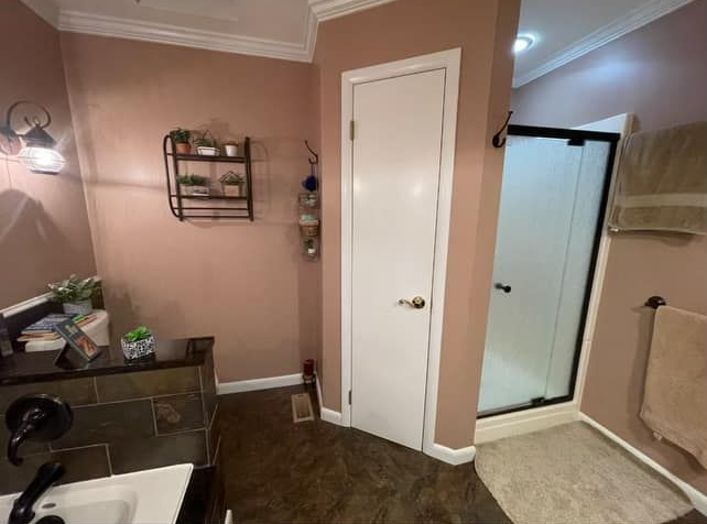 Bathroom with pink walls, white door, and a black framed shower.