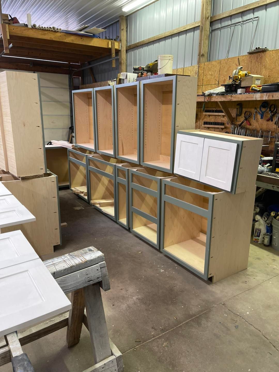 Cabinet boxes in a workshop, with white cabinet doors and exposed wooden interiors.