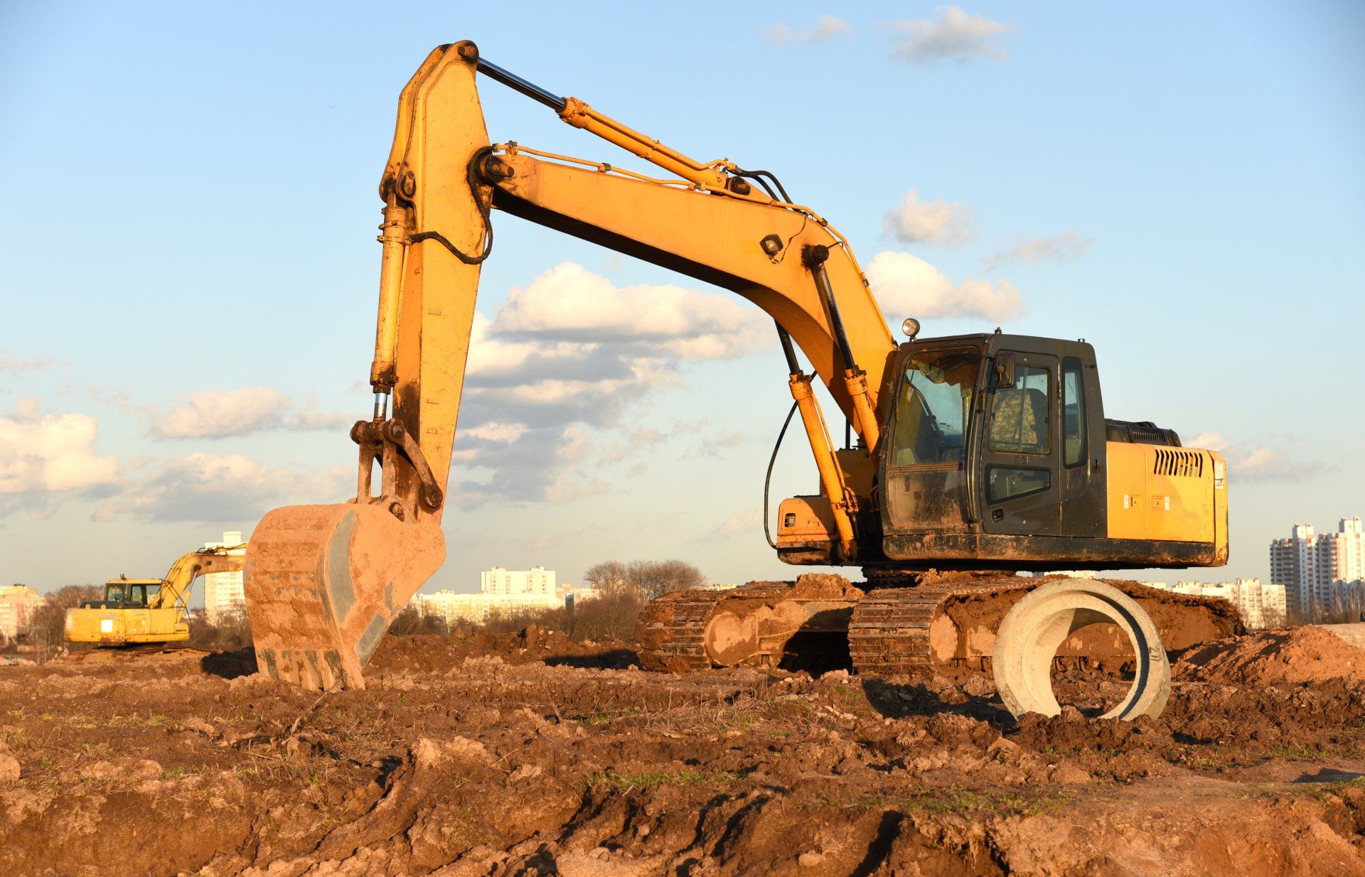 Une excavatrice jaune travaille sur un chantier de construction.