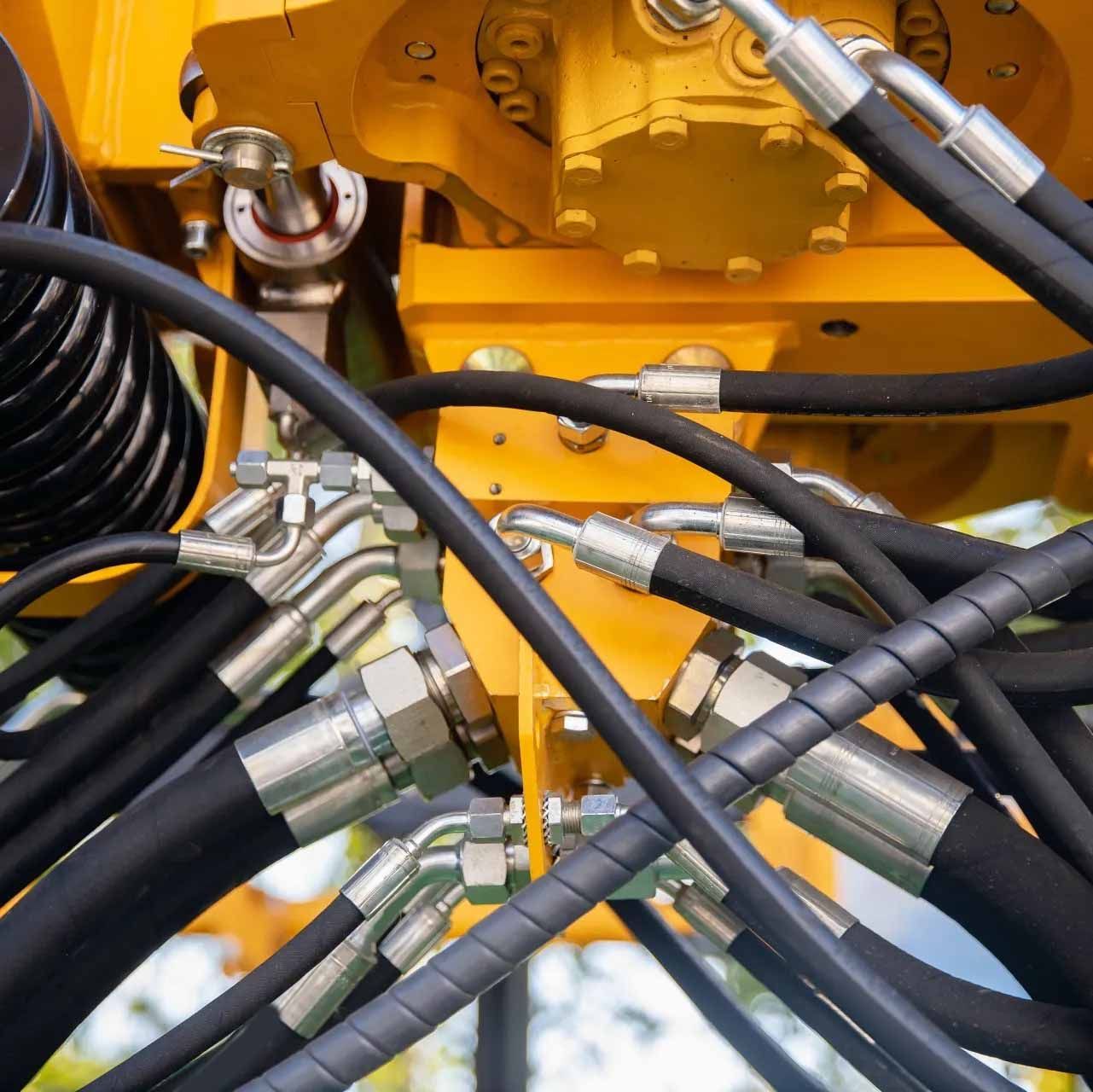 A bunch of hydraulic hoses are connected to a yellow machine