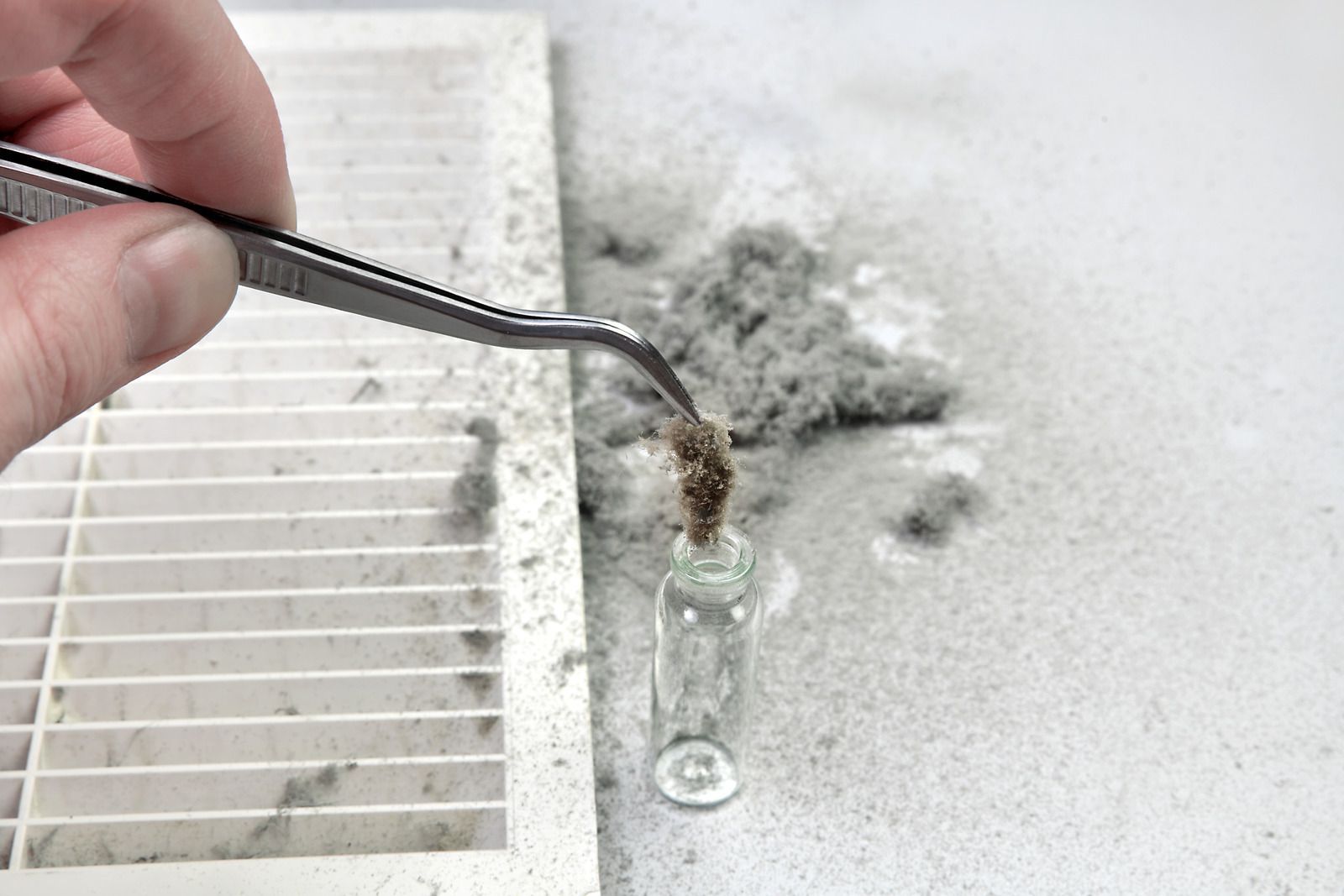 A person is cleaning a dirty air filter with tweezers.
