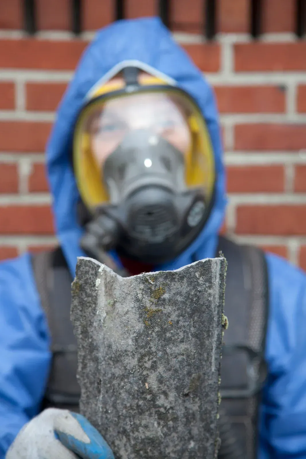 A man wearing a gas mask is holding a piece of concrete