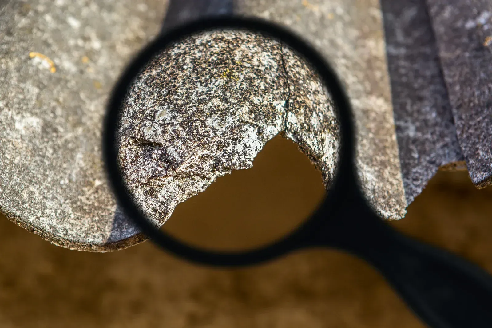 A magnifying glass is being used to look at a piece of metal.