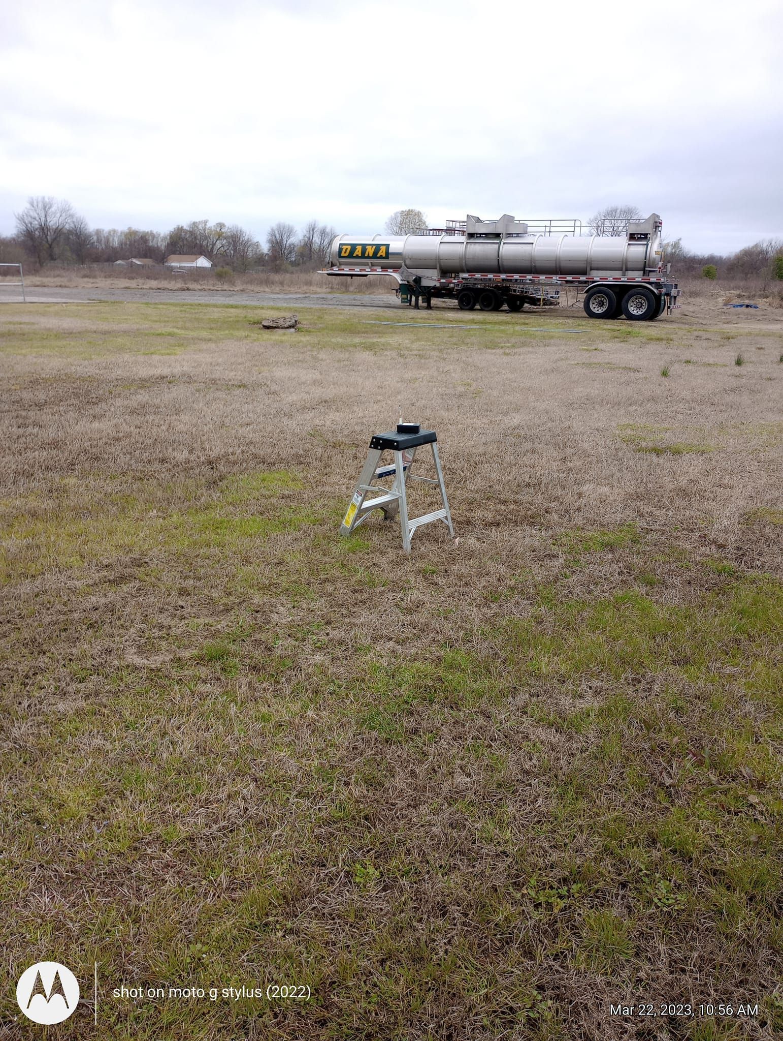 A tanker truck is parked in the middle of a grassy field.