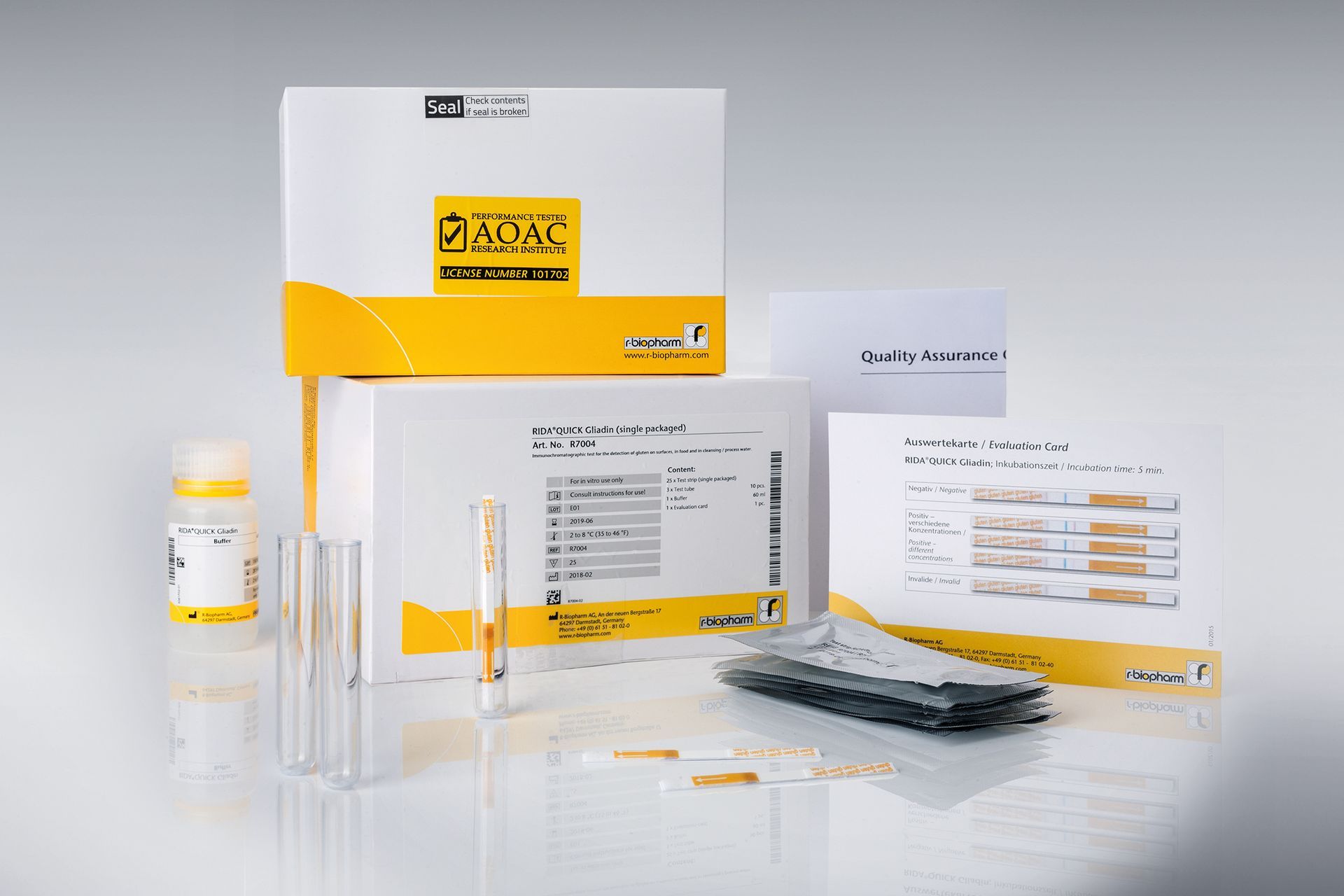 Diagnostic test kit: white and yellow boxes, tubes, and testing strips on a reflective surface.