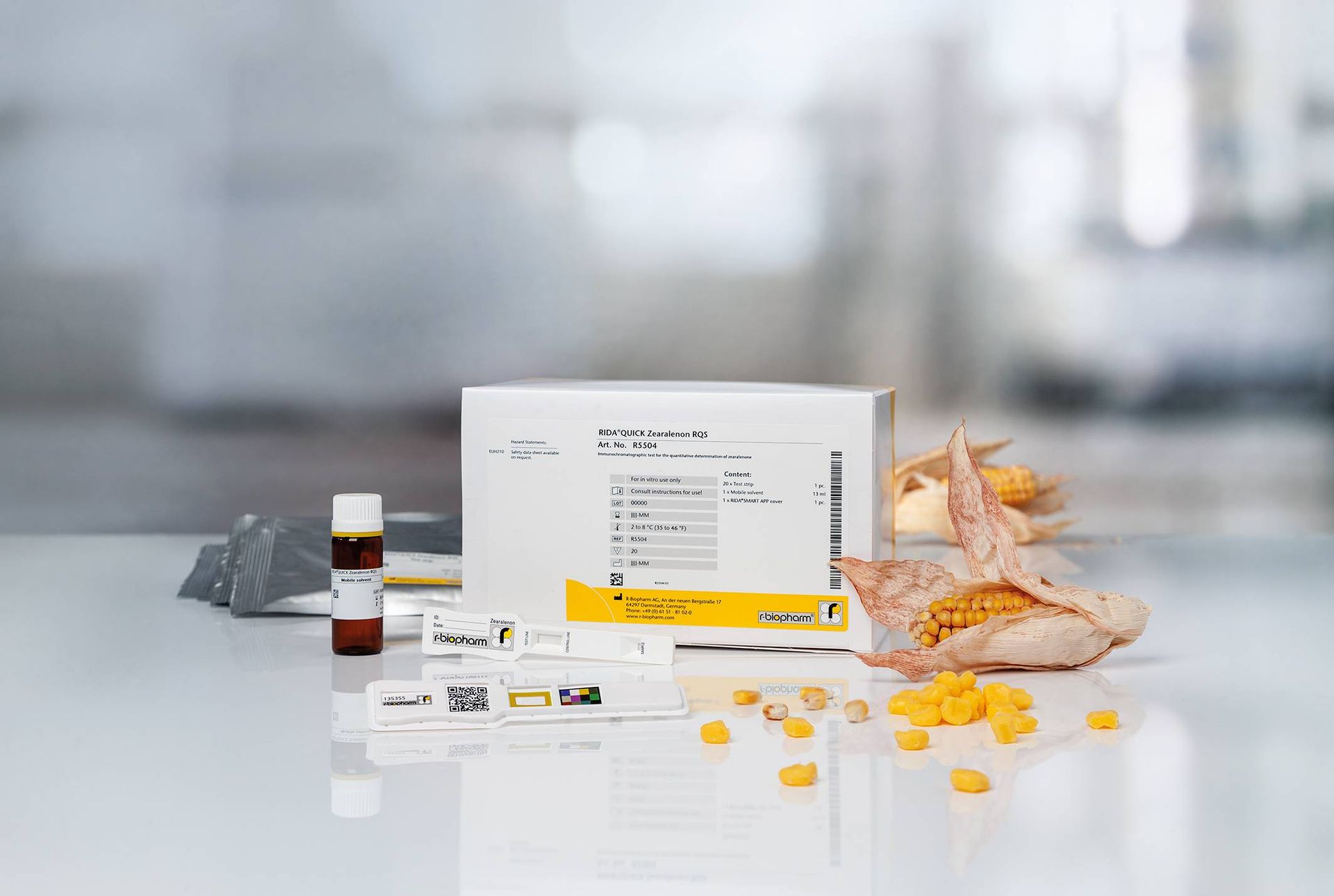 Boxed corn testing kit with corn kernels scattered in a bright, sterile environment.