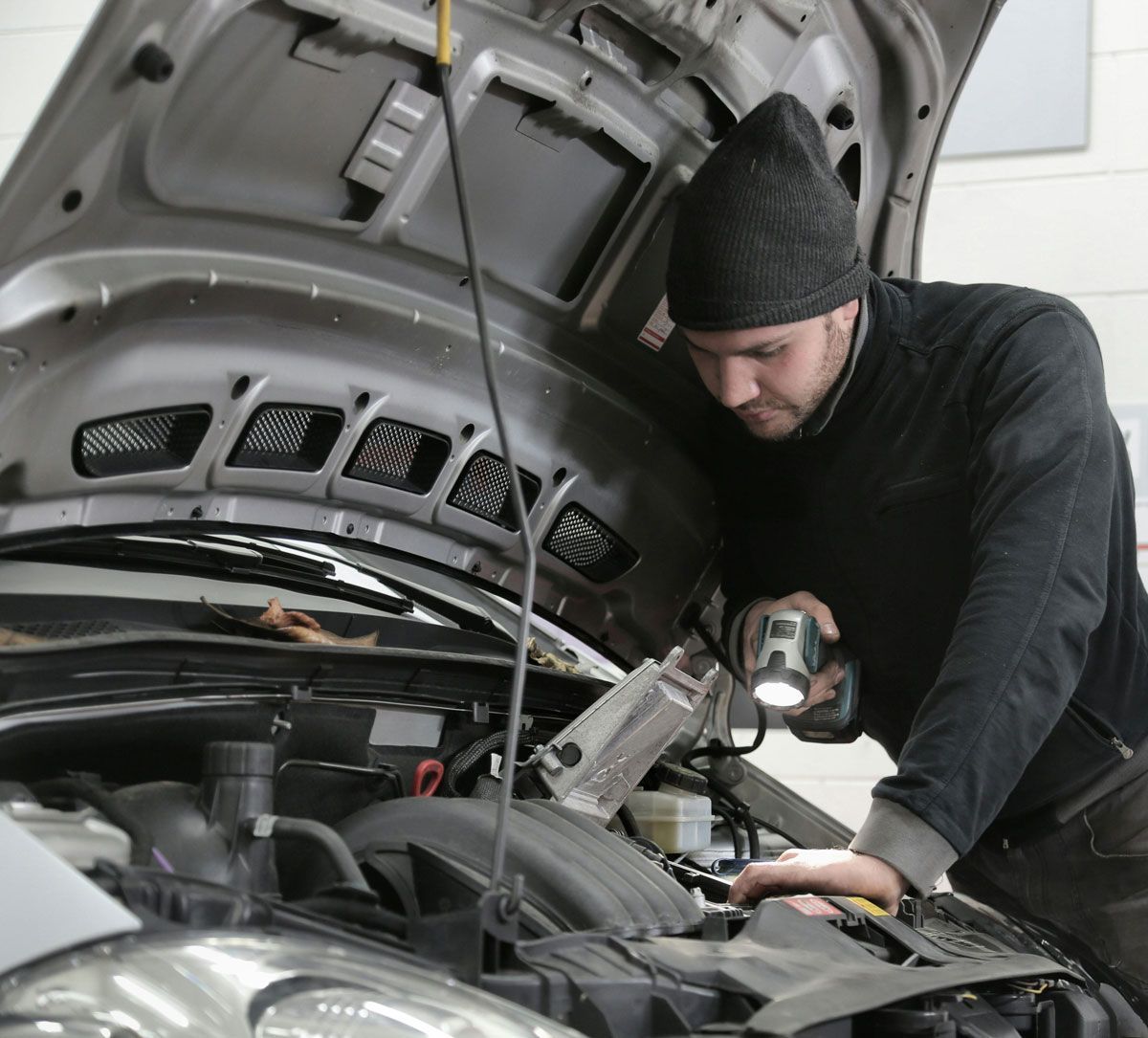 A man is working under the hood of a car