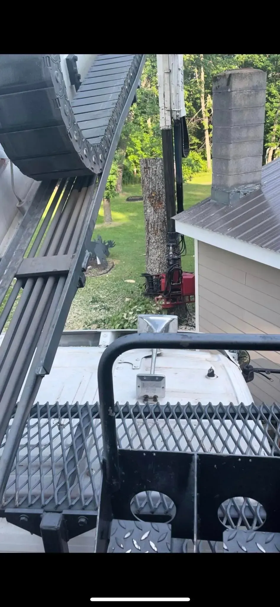 A crane is lifting a tree in front of a house.