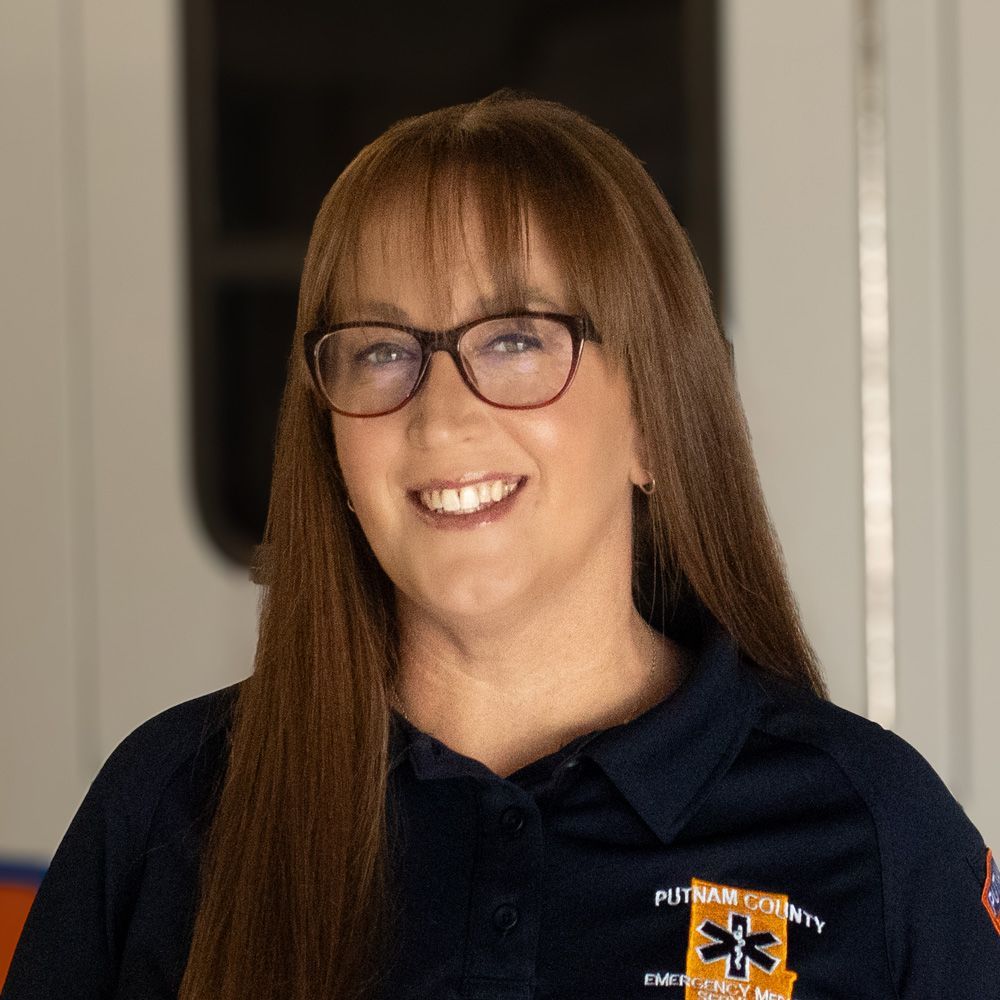 Smiling person with glasses in a navy shirt standing indoors