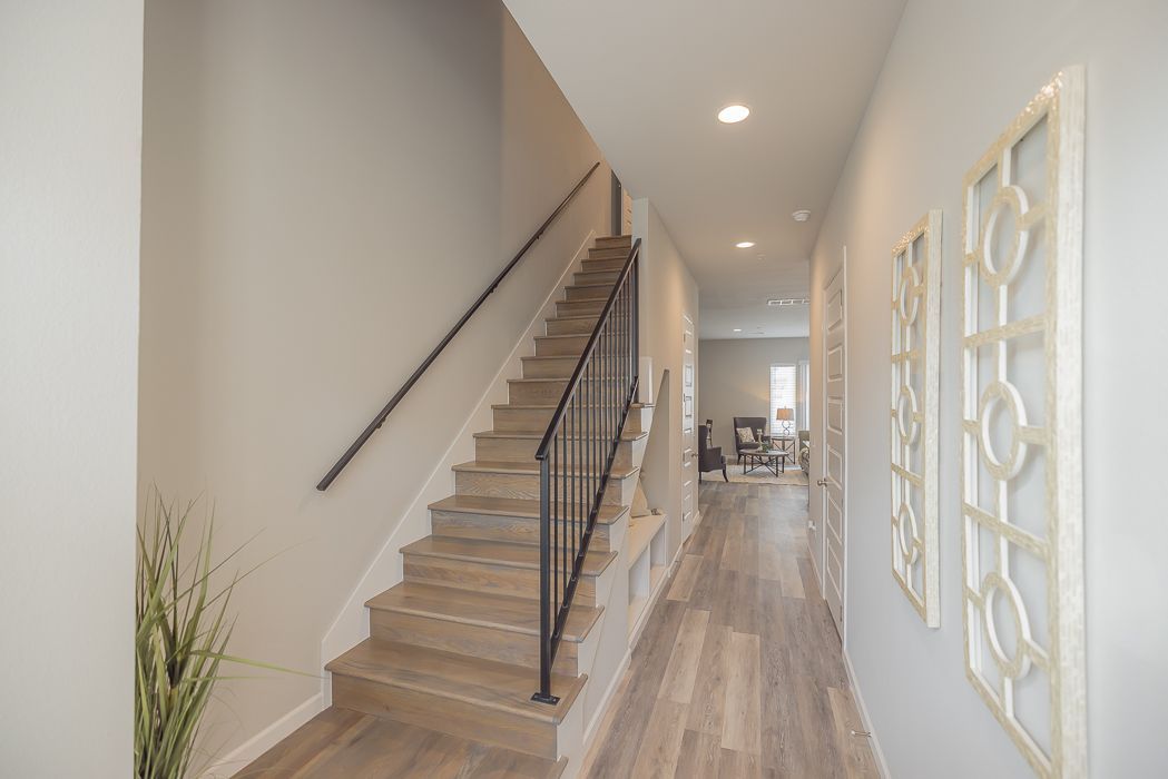 Hallway with staircase and decorative wall art. Light wood flooring, neutral walls.