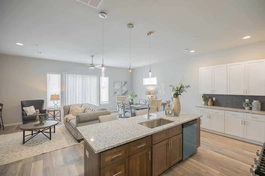 Open-concept living space with kitchen island, sofa, and dining area; neutral colors.