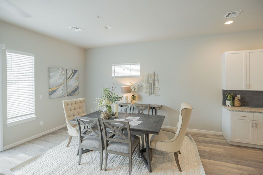 Dining room with table and chairs on a rug, neutral color scheme, window with blinds, and a cabinet.