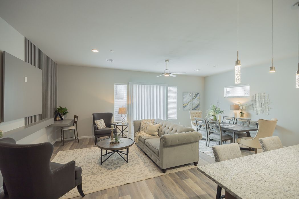 Open-concept living space with neutral tones; includes seating area, dining table, and kitchen island.