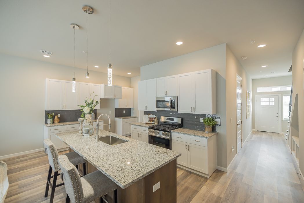 Modern kitchen with white cabinets, granite island, and stainless steel appliances.