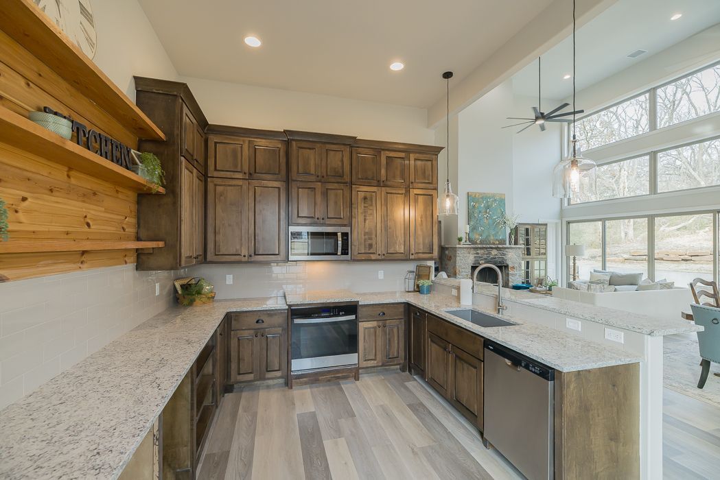 Kitchen with wood cabinets, light countertops, stainless steel appliances, and a large window.