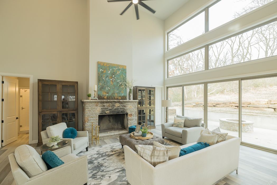 Spacious living room with fireplace, large windows, and modern furniture overlooking a natural outdoor area.