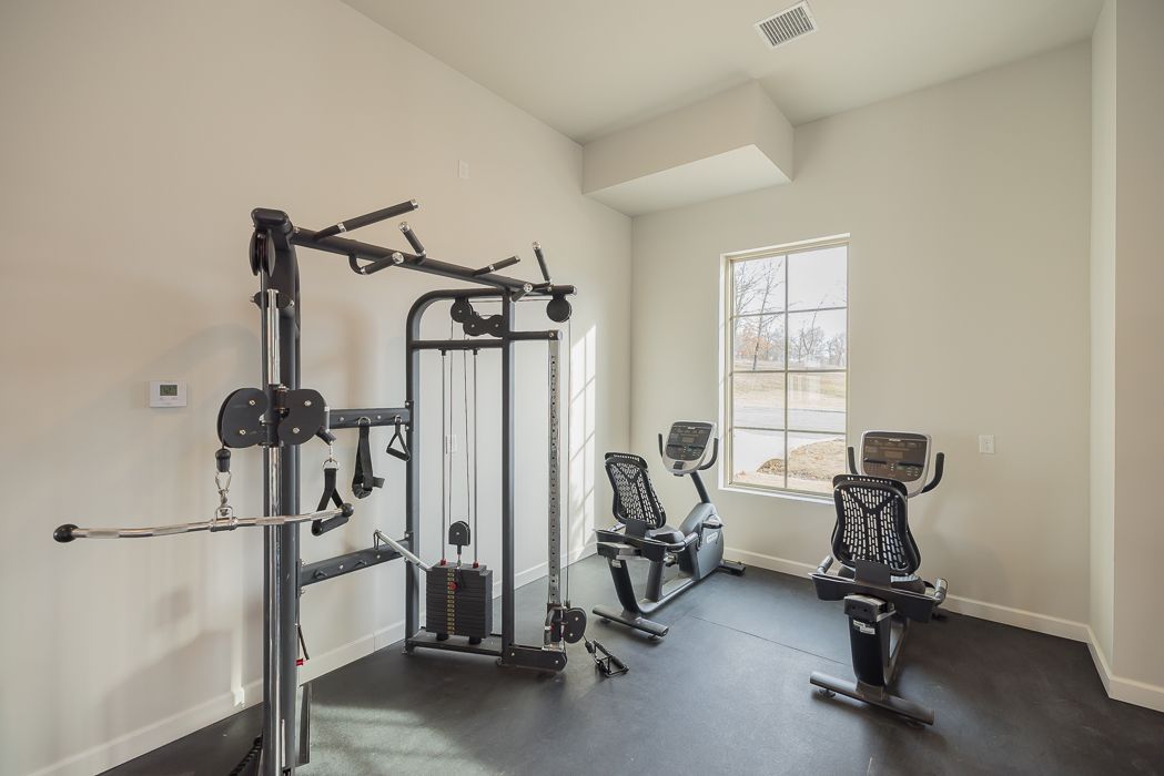 Home gym with weight machine, exercise bikes, and window.