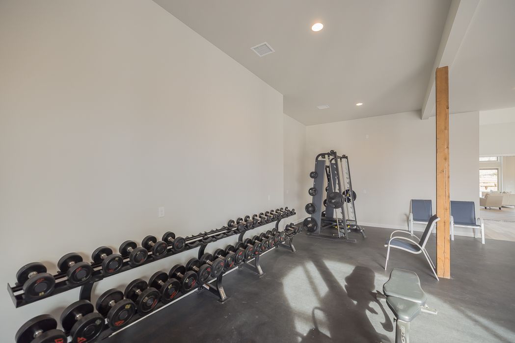Dumbbell rack and weight machine in a home gym with two chairs.