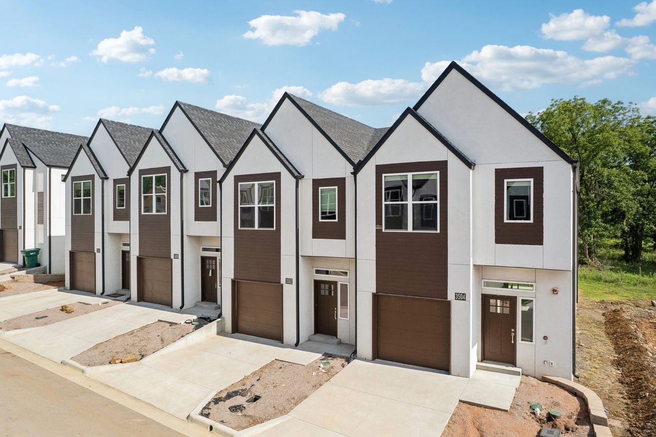 Row of modern townhomes with white walls, brown accents, and a blue sky.