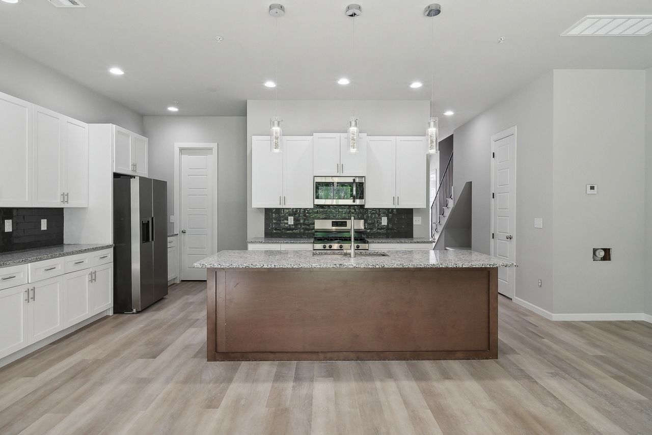 Modern kitchen with white cabinets, brown island, granite countertops, and stainless steel appliances.