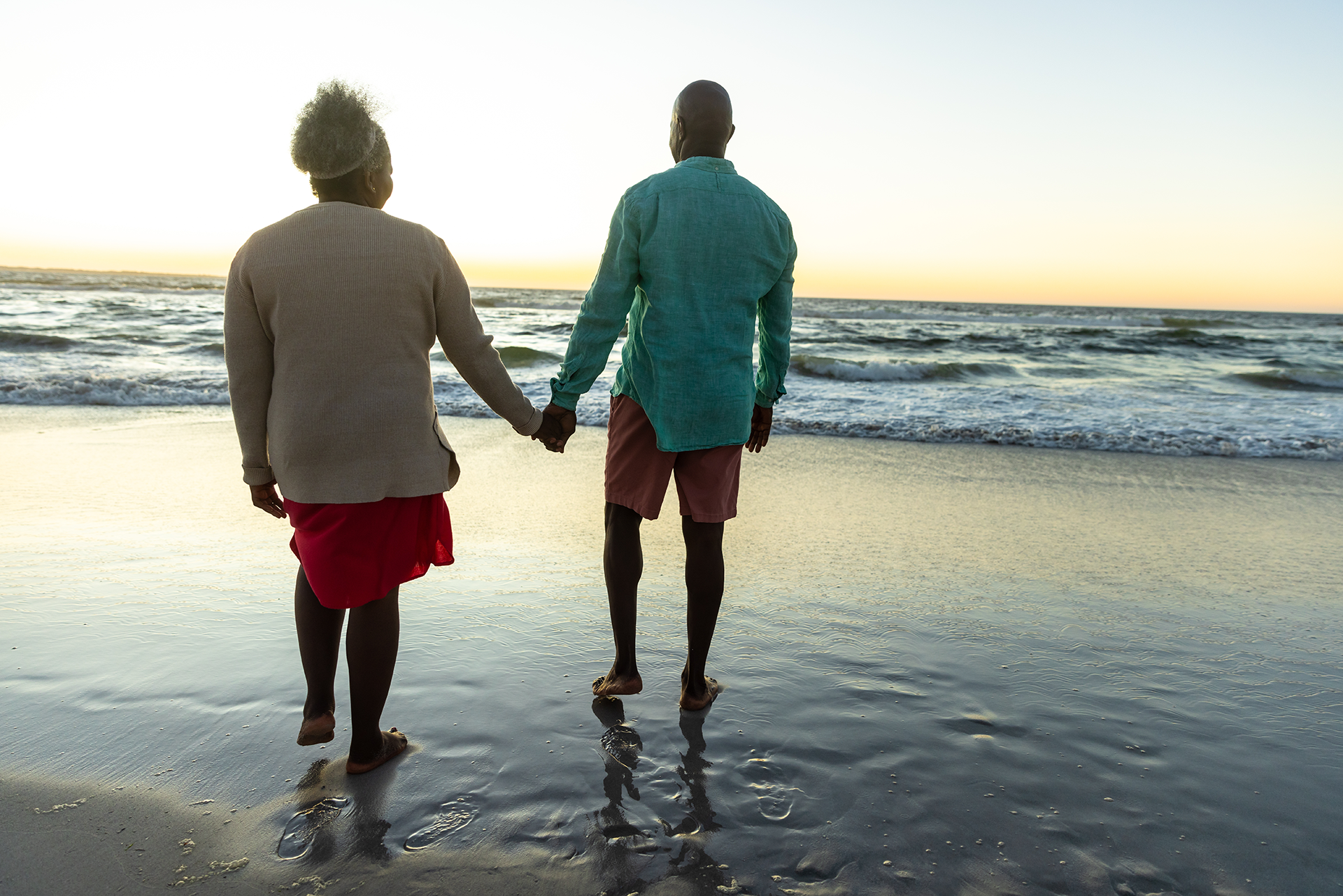 A boy is running towards an elderly couple sitting on a blanket in the grass.