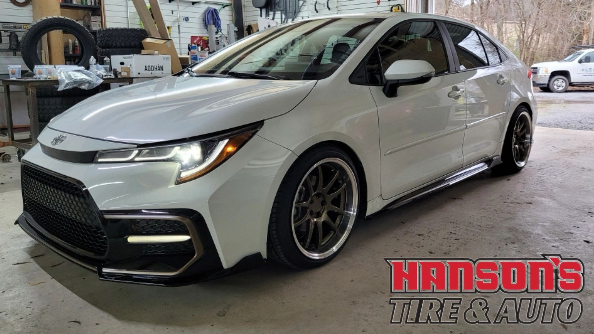 A white toyota corolla is parked in a garage.