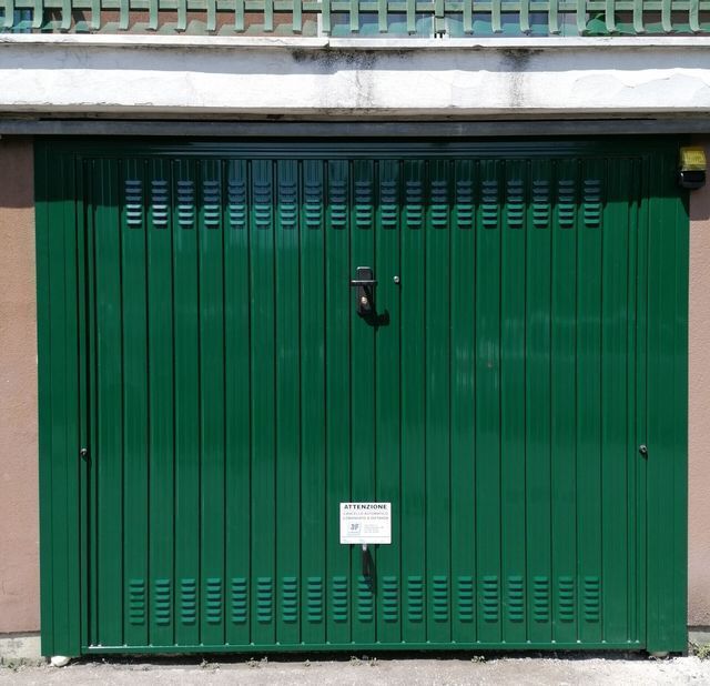 Porta da garage verde con linee verticali e maniglia.