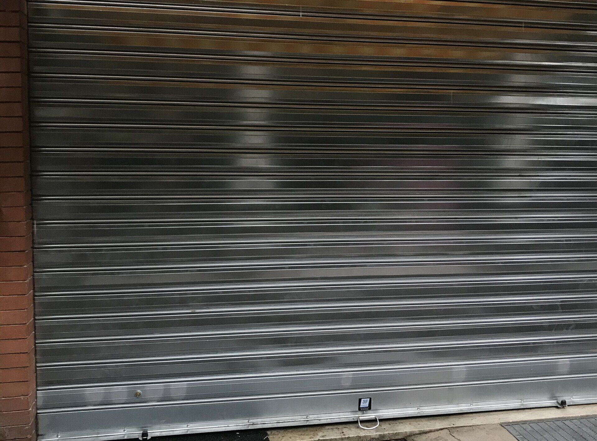 Serranda di sicurezza del negozio in metallo argentato chiusa.