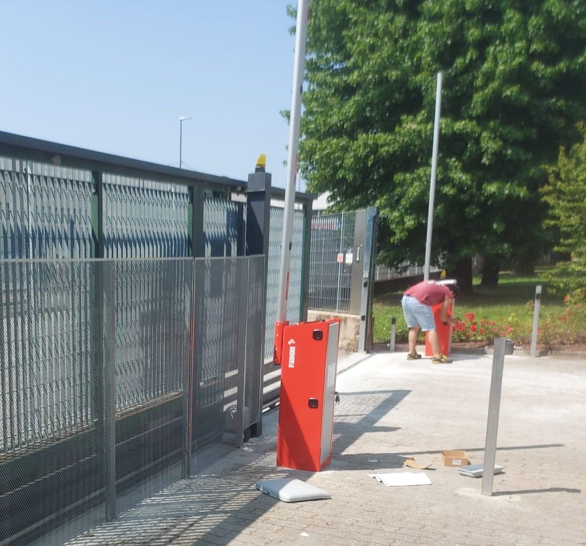 Cancello con braccio di sbarramento, centralina di controllo rossa.