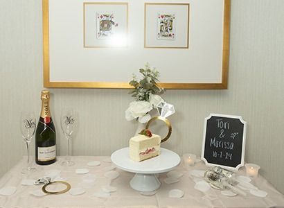 Engagement celebration with cake, champagne, and ring décor. A framed picture hangs above.