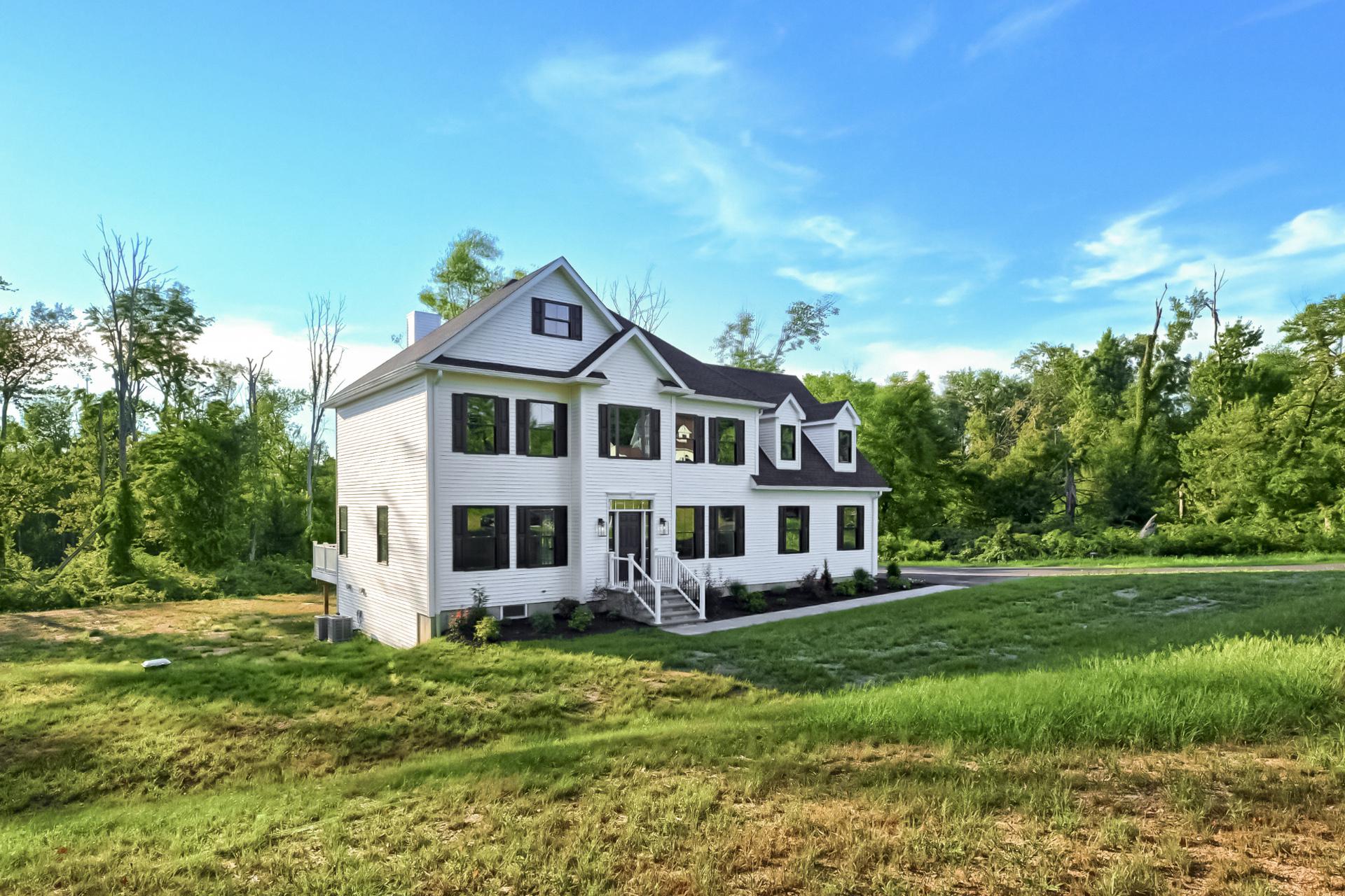 A large white house sits in the middle of a lush green field