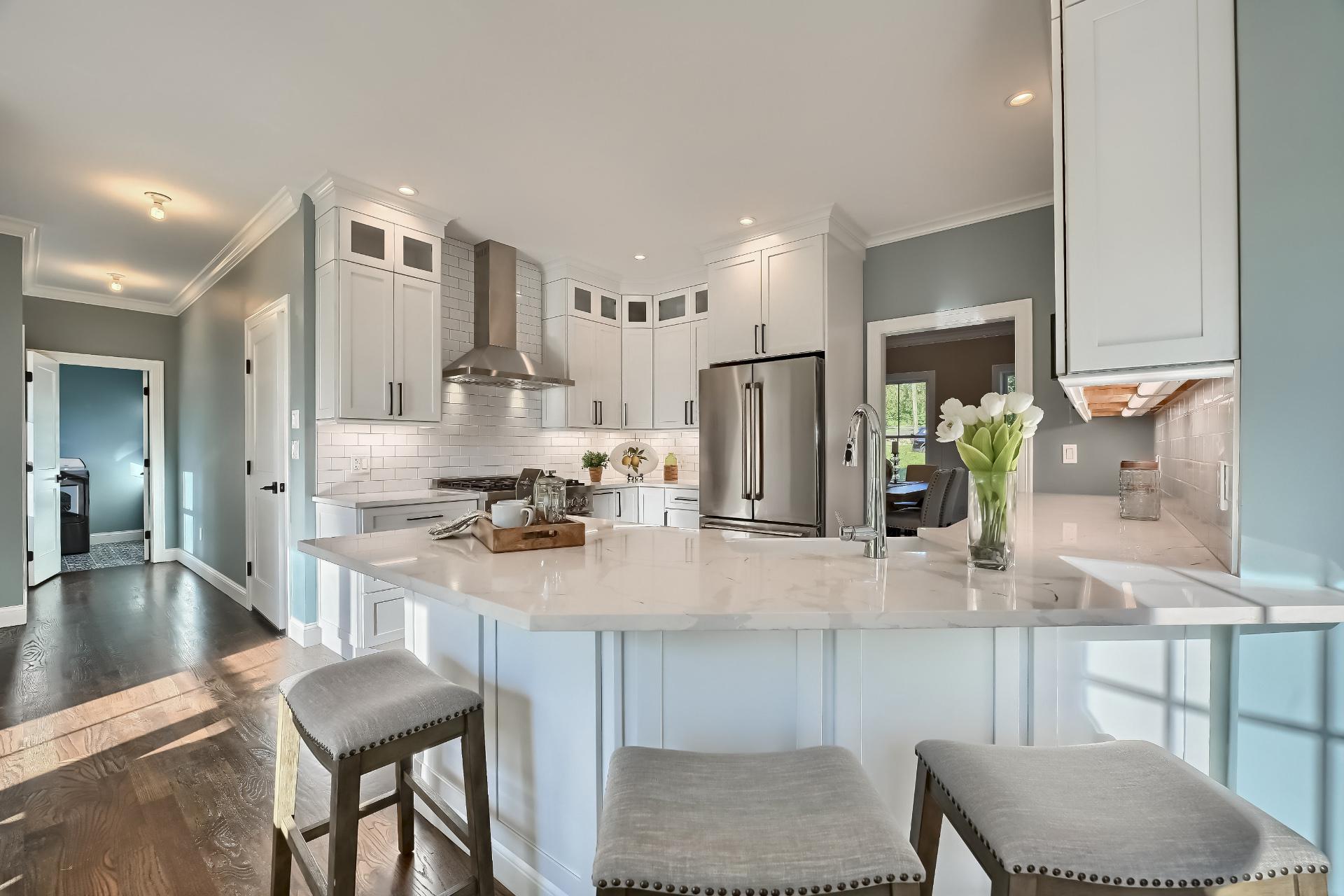 A kitchen with white cabinets and stools and a large island.