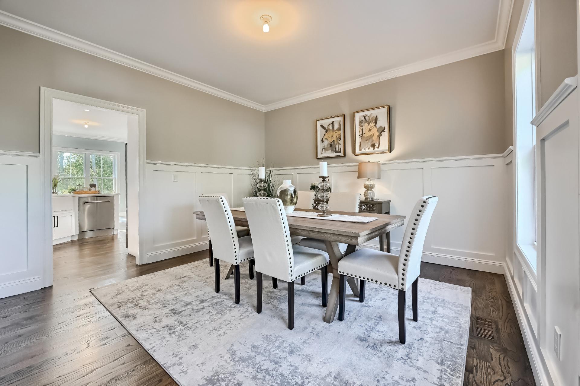 A dining room with a table and chairs and a rug.