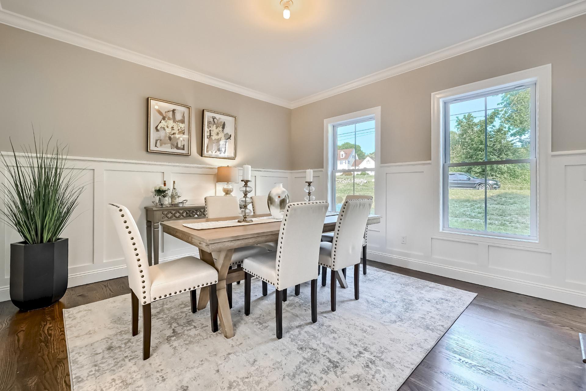 A dining room with a table and chairs and a rug.
