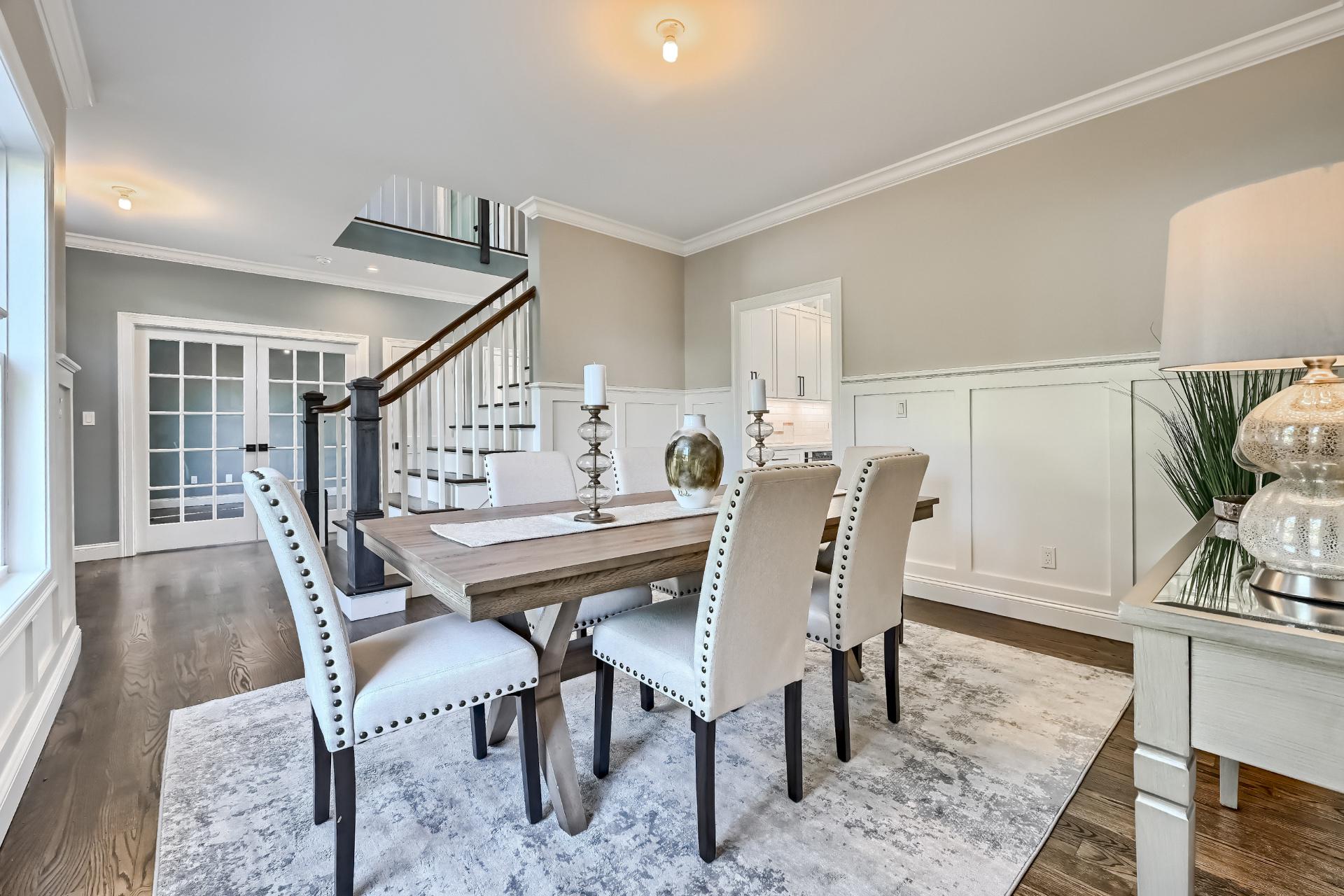 A dining room with a table and chairs and a staircase.