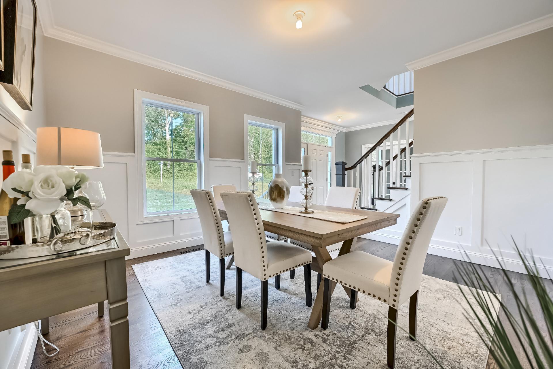 A dining room with a table and chairs and a staircase.
