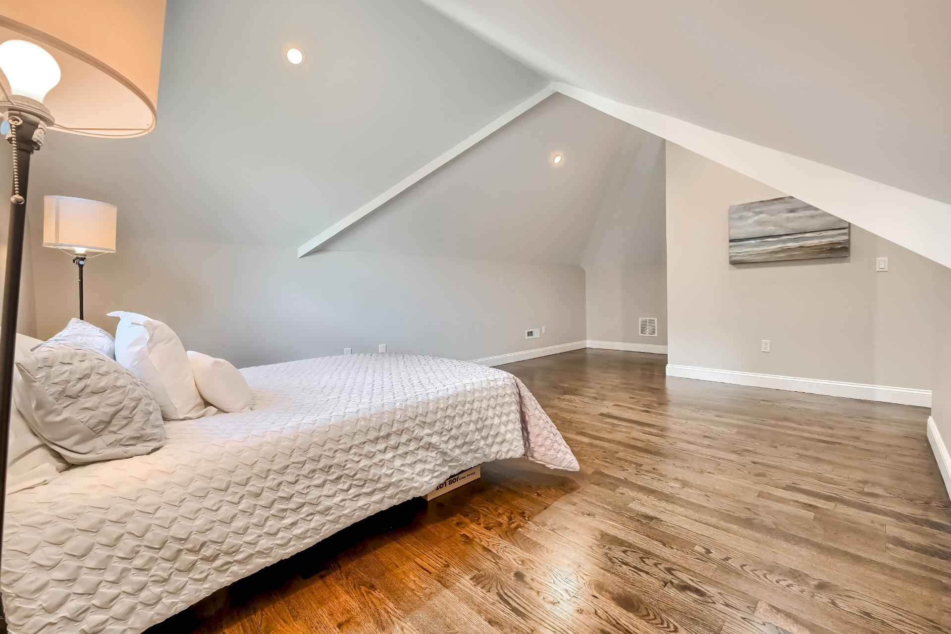 A bedroom with a bed , lamp , and a picture on the wall.